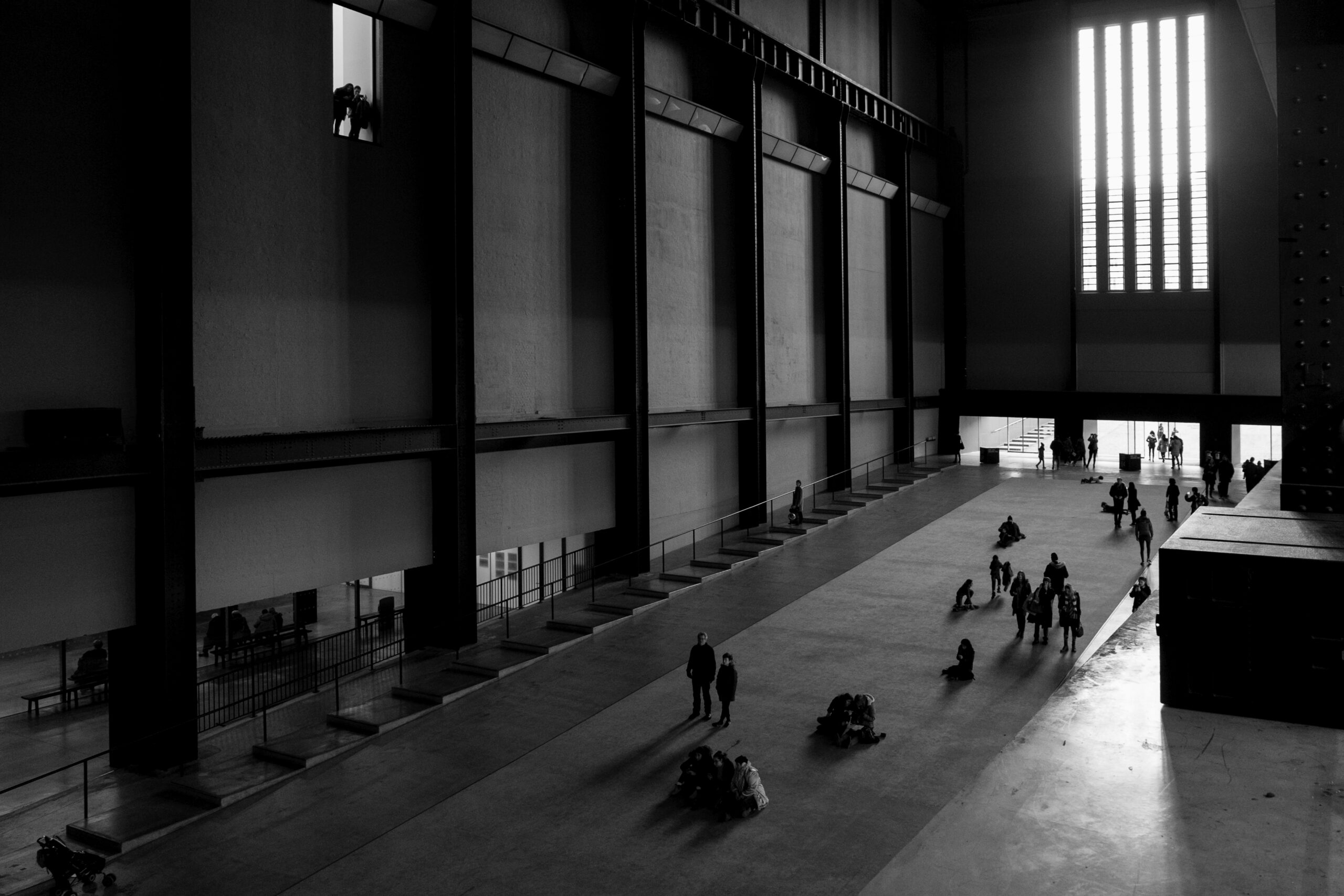 People standing on a ramp looking up inside the main hall at the Tate Modern Gallery in London.